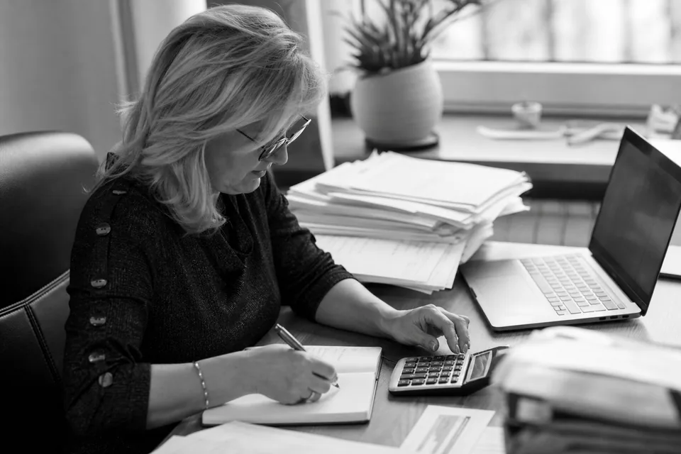Właścicielka małej firmy liczy koszty na kalkulatorze przy biurku z fakturami