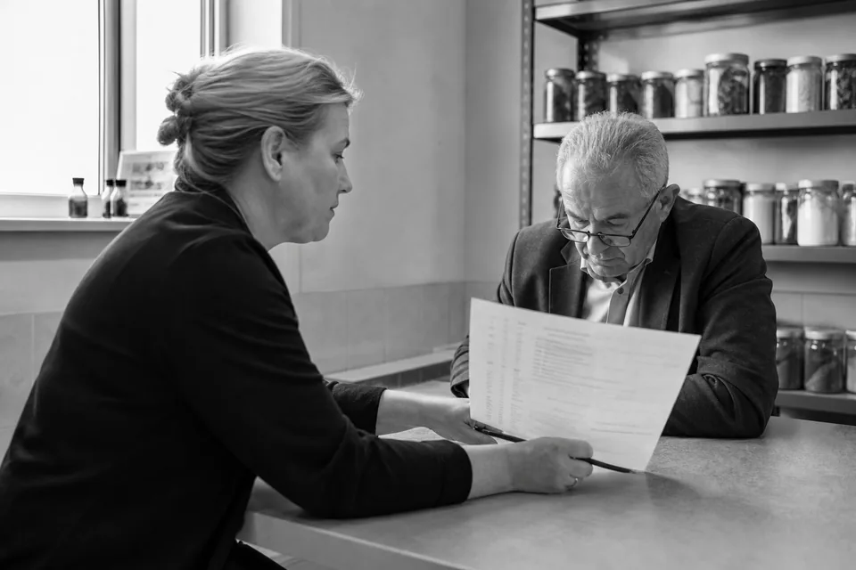 Właścicielka firmy produkcyjnej pokazuje inwestorowi wydruk wyników spółki przy stole w sali konferencyjnej