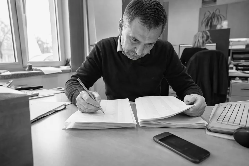 Handlowiec porównuje dwa wydruki list firm przy biurku